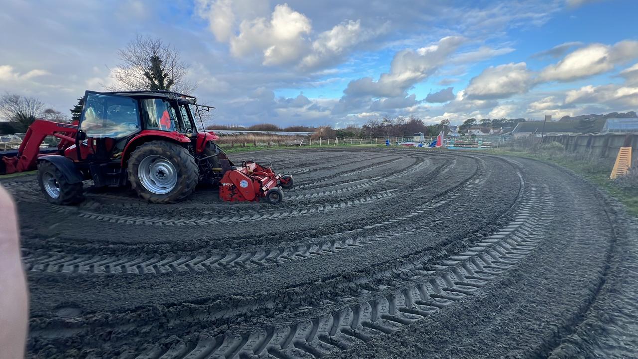 Stonebridge & Sons tractor with flail topper working a sand arena, tidy overlapping tracks visible